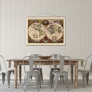 May include: A vintage world map print hangs above a rustic wooden dining table with four gray metal chairs. The map is framed in a simple brown frame and features a detailed depiction of the continents.