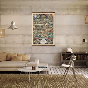 May include: A vintage map of Somerset, England, printed in blue, red, and yellow colors, framed and hanging on a wall in a living room setting. The map is surrounded by a light brown wood frame.
