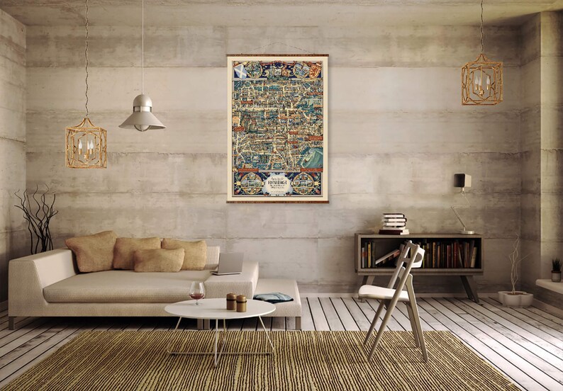 May include: A vintage map of Somerset, England, printed in blue, red, and yellow colors, framed and hanging on a wall in a living room setting. The map is surrounded by a light brown wood frame.
