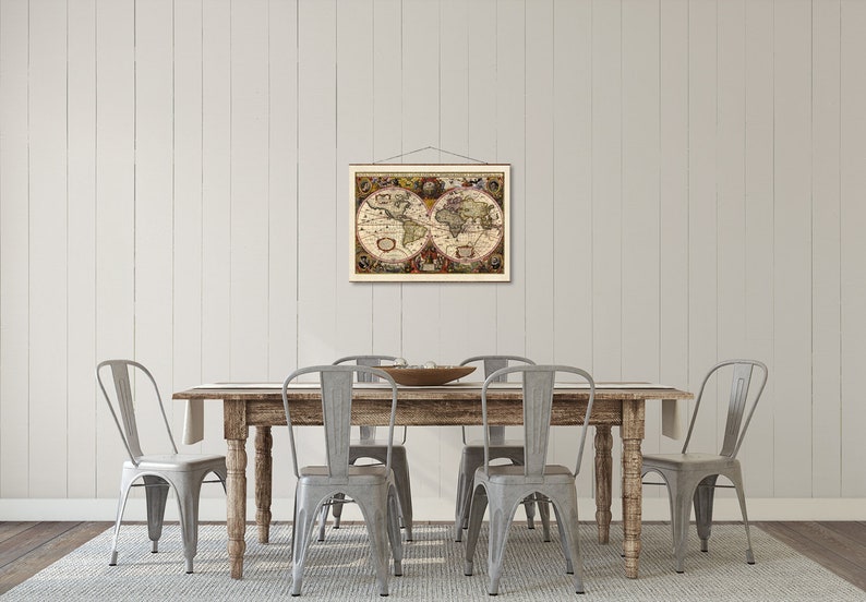 May include: A vintage world map print hangs above a rustic wooden dining table with four gray metal chairs. The map is framed in a simple wooden frame and features a detailed depiction of the world with landmasses and oceans.