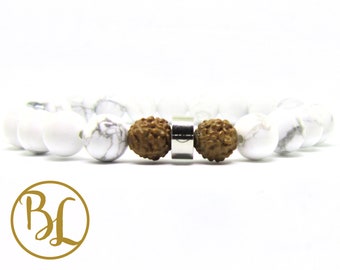 May include: White and gray marble-like beaded bracelet with two brown, textured beads and a silver-colored metal accent. The bracelet is on a white background. The bracelet is a piece of jewelry.