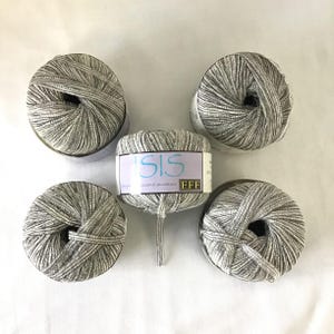 May include: Five skeins of yarn in a neutral color palette. The yarn is a mix of gray and white, with a subtle striped pattern. One skein has a label that reads "ISIS" in blue script. The yarn is suitable for knitting and crochet projects.