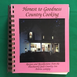 May include: A spiral-bound cookbook titled "Honest to Goodness Country Cooking" with a pink cover. The cover features a nighttime image of a house with lights on. The text "Recipes and Recollections from the Patchwork Quilt Country Inn Arletta Lovejoy" is also visible.