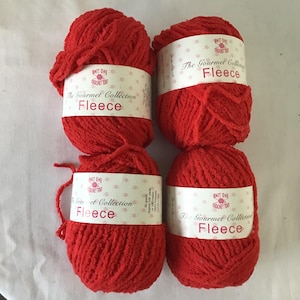 May include: Four balls of red fleece yarn are stacked in two rows of two. Each ball has a white label with the text "KNIT ONE CROCHET TOO The Gourmet Collection Fleece". The yarn is a vibrant, solid red color.