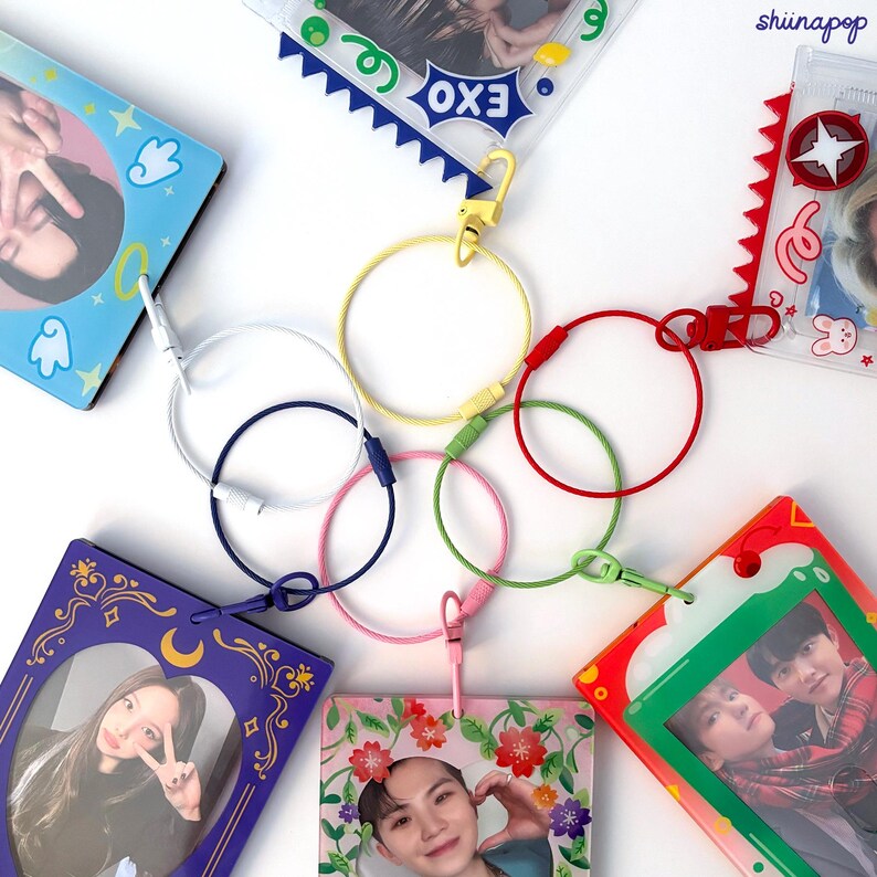 May include: A set of colorful keychains with different designs. Each keychain features a small photo card with a different image. The keychains are connected by a series of metal rings in various colors, including white, blue, green, pink, and yellow.
