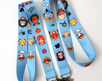 May include: Two blue and white lanyards with cartoon characters from the anime One Piece. The lanyards feature characters like Luffy, Zoro, Sanji, and Chopper. The lanyards have a black clip and a black swivel hook.
