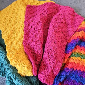May include: A multi-colored crocheted blanket with stripes of teal, yellow, pink, and rainbow colors.