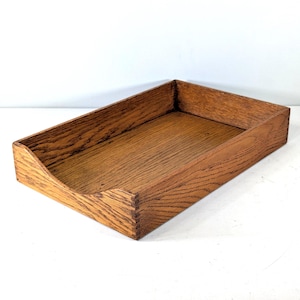 Peut inclure: Un plateau de bureau rectangulaire en bois de chêne aux tons moyens avec un motif de grain de bois visible. Le plateau présente des coins à joints carrés et une découpe incurvée sur le panneau avant pour un accès facile au contenu.