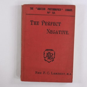 Puede incluir: Un libro rojo titulado "The Perfect Negative" de "The Amateur Photographer Library" número 19. El libro es de Rev. F.C. Lambert, M.A.