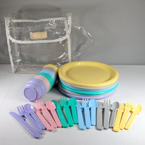 May include: A set of pastel-colored plastic plates, bowls, cups, forks, spoons, and knives, all neatly arranged on a white surface. The set is packaged in a clear plastic bag.