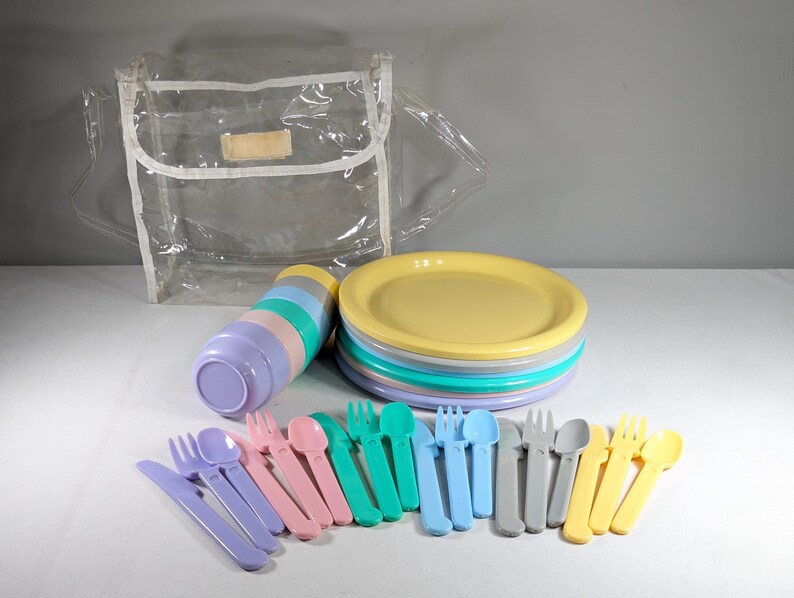May include: A set of pastel-colored plastic plates, bowls, cups, forks, spoons, and knives, all neatly arranged on a white surface. The set is packaged in a clear plastic bag.