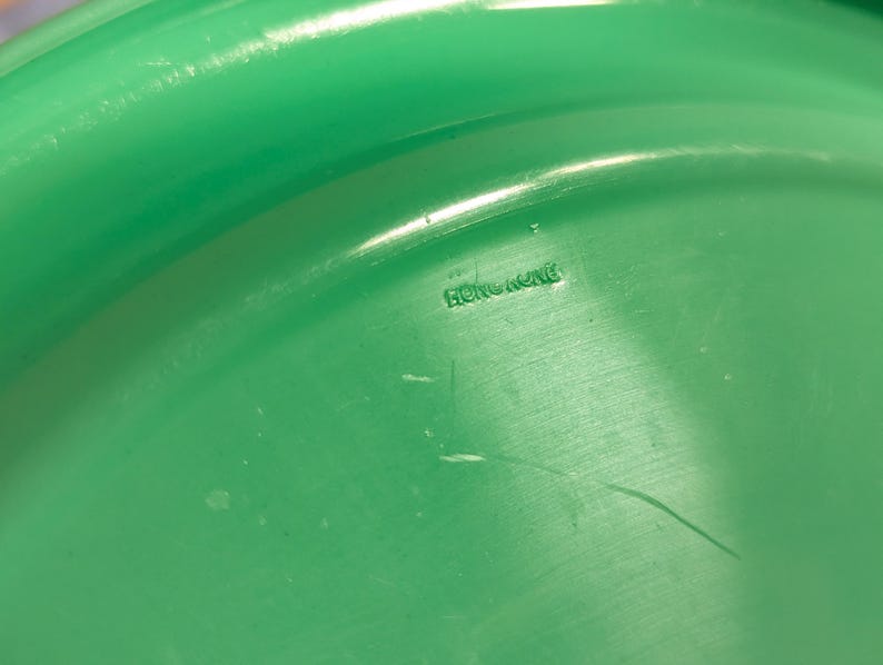 May include: Close-up of a green plastic disc with the words "Hong Kong" printed on the underside.