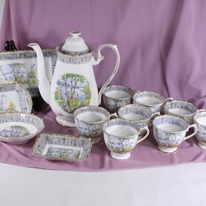 Könnte beinhalten: Ein weißes Porzellan-Tee-Set mit einem Blumenmuster. Das Set enthält eine Teekanne, eine Zuckerdose, eine Milchkännchen und sechs Teetassen und Untertassen.