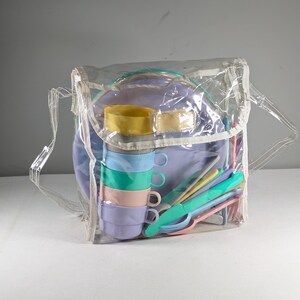 May include: A clear plastic bag containing a set of colorful plastic plates, cups, and utensils. The set is designed for children and is perfect for picnics or outdoor play.
