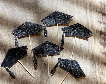 May include: Six black glitter graduation cap cupcake toppers with wooden sticks.