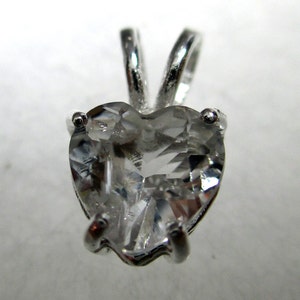 May include: A silver heart-shaped pendant with a clear crystal stone.