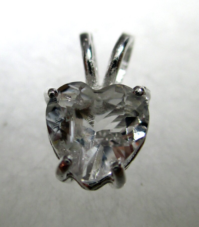 May include: A silver heart-shaped pendant with a clear crystal stone.