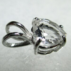 May include: A silver pendant with a clear pear-shaped gemstone. The pendant has a bail with a loop for attaching a chain.