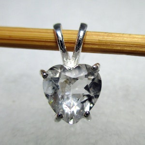 May include: A silver heart-shaped pendant with a clear crystal stone.