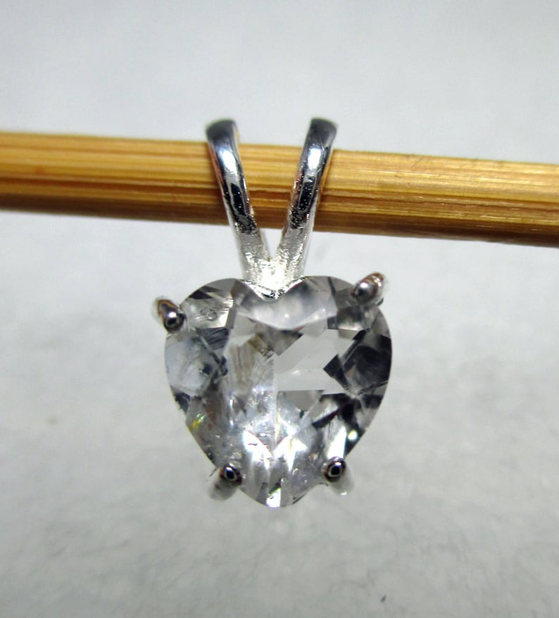 May include: A silver heart-shaped pendant with a clear crystal stone.