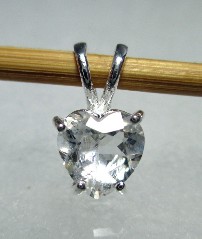 May include: A silver heart-shaped pendant with a clear crystal stone.