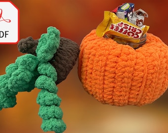 May include: An orange, plush, pumpkin-shaped container filled with candy. The pumpkin has a textured surface and is accompanied by a green and brown crocheted vine. A PDF icon is in the upper left corner.