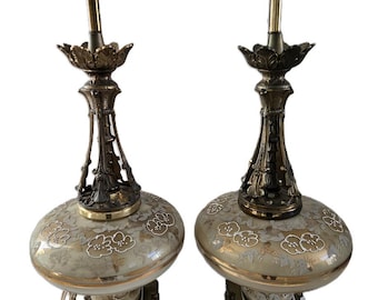May include: A pair of vintage table lamps with a gold and white floral design on the glass shades. The lamps have a brass base with a marble top.