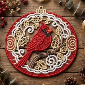 May include: Embroidered Christmas ornament featuring a red cardinal bird perched on a branch. The ornament has a red background with white and gold filigree detailing. A festive holiday decoration.