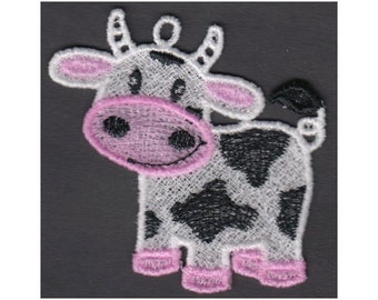 May include: Embroidered design of a white cow with black spots and pink accents. The cow is standing with its head turned to the side and its tongue sticking out. The design is perfect for a variety of embroidery projects.
