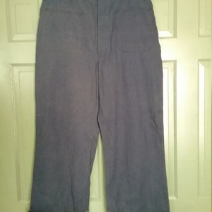 May include: A pair of dark blue pants with cuffed legs. The pants have a button fly and two front pockets.