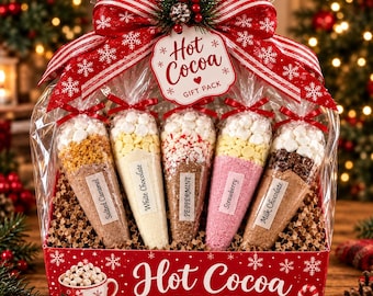 May include: A hot cocoa gift pack in a red box with white snowflake patterns, containing five clear cone-shaped bags filled with cocoa mix, marshmallows, and toppings labeled Salted Caramel, White Chocolate, Peppermint, Strawberry, and Milk Chocolate.