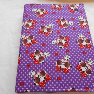 May include: A purple fabric item featuring a white polka dot pattern. The fabric is adorned with cartoon dog illustrations wearing sunglasses and red bow ties. Small red hearts are scattered across the design.