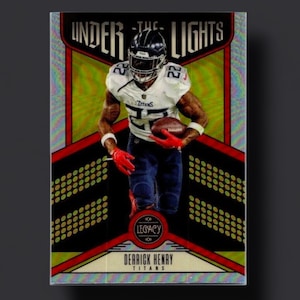 May include: A football trading card featuring Derrick Henry of the Tennessee Titans. The card has a red, gold, and black design with the words "UNDER THE LIGHTS" at the top. Henry is shown in his uniform, holding a football.