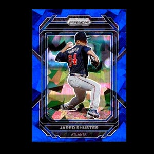 May include: A Panini Prizm baseball card featuring Jared Shuster of the Atlanta Braves in a throwing pose. The card has a blue geometric design with the Prizm logo at the top. The player is wearing a navy blue jersey with the number 84.