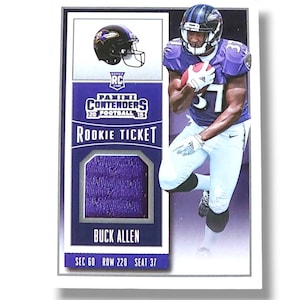May include: A purple and white football card featuring a photo of a football player wearing a purple jersey and white pants. The card has the text "ROOKIE TICKET" and "BUCK ALLEN" on it. The card also has the text "SEC 60 ROW 220 SEAT 37" on it.