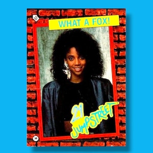May include: A vintage trading card featuring a woman with curly black hair, wearing a black top and a blue jacket. The card has the text "WHAT A FOX!" and "21 JUMPSTREET" on it, set against a brick wall background.