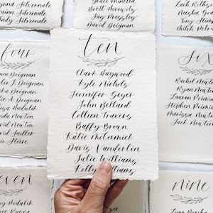 May include: Ten cards with handwritten calligraphy on each. The cards are labeled with the numbers four, seven, ten, six, and nine. Each card has a list of names written in cursive.