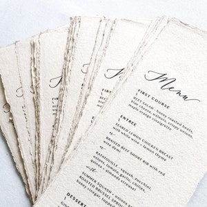 May include: A wedding menu printed on textured paper with a handwritten font. The menu includes a first course, entree, and dessert bar. The first course is beet salad, the entree is seared lemon chicken breast or braised beef short rib, and the dessert bar includes a ginger and spices wedding cake, pecan praline buttercream, mini strawberry shortcake, creme brulee shooter, mini milk chocolate cookies, and fresh berry parfait.