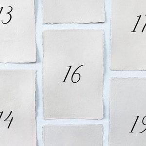 Printed wedding table numbers on handmade paper for a modern and minimalist wedding reception or rehearsal dinner