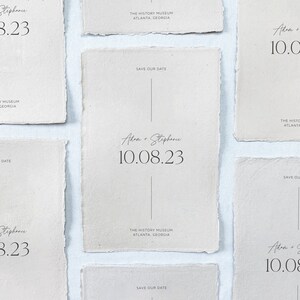 May include: Five save the date cards with a rustic, cream-colored paper texture. Each card features the text "Adam + Stephanie" and the date "10.08.23" in a handwritten font. The text "The History Museum, Atlanta, Georgia" and "Save Our Date" are also included on each card.