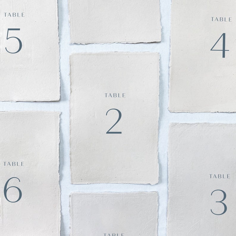May include: Five beige table number cards with the words "TABLE" and the numbers 2, 3, 4, 5, and 6 printed in blue.