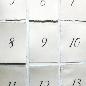 May include: A set of 13 white paper cards with black numbers from 5 to 13. The cards are arranged in a grid pattern.