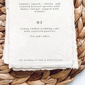 K&ouml;nnte beinhalten: Eine wei&szlig;e Karte mit dem Text "Summer squash + onions and roasted brussel sprouts with honey vinegar, topped with walnuts" und "03 Lemon chiffon wedding cake with assorted pastries Tea and coffee The Wedding of Emily & David Stevens" auf einem gewebten braunen Hintergrund.