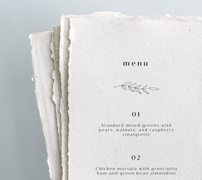 K&ouml;nnte beinhalten: Eine einfache Speisekarte mit handschriftlicher Schrift auf einem strukturierten Papierhintergrund. Die Speisekarte listet zwei Gerichte auf: Standard-Gemischter Salat mit Birnen, Waln&uuml;ssen und Himbeer-Vinaigrette und H&auml;hnchen Marsala mit Prosciutto-Schinken und gr&uuml;nen Bohnen mit Mandel.