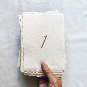 May include: A stack of white paper cards with a brown number "1" printed on the front.