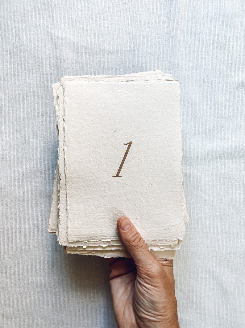 May include: A stack of white paper cards with a brown number "1" printed on the front.