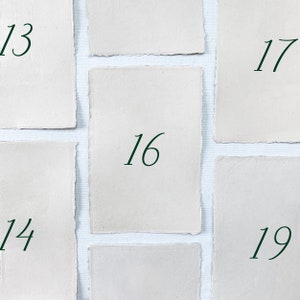 May include: Nine white paper cards with numbers 13, 14, 16, 17, 19 written in green ink on each card.