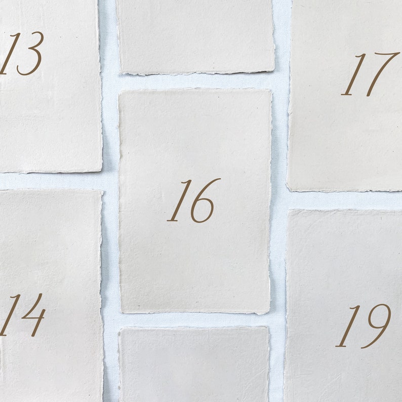 May include: Five white paper squares with numbers 13, 14, 16, 17, and 19 written on them.