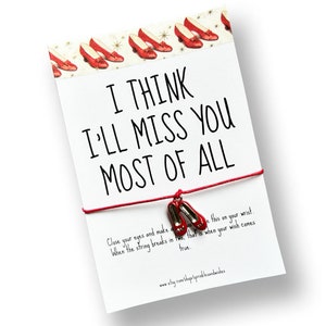 May include: Red string bracelet with a charm of red shoes. The card attached to the bracelet reads "I think I'll miss you most of all. Close your eyes and make a wish. When the string breaks in two, that is when your wish comes true."