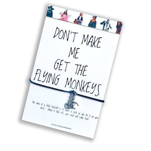 May include: A black string bracelet with a silver charm of a monkey. The bracelet has a card attached to it that reads "Don't make me get the flying monkeys." The card also explains that the bracelet is a wish bracelet and that when it falls off, your wish will come true.